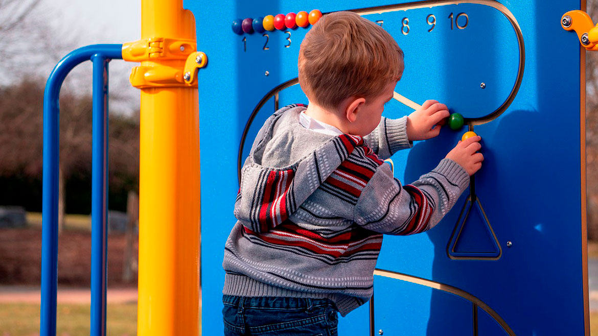 Preschool kid boy in colorful clothes playing outdoors during